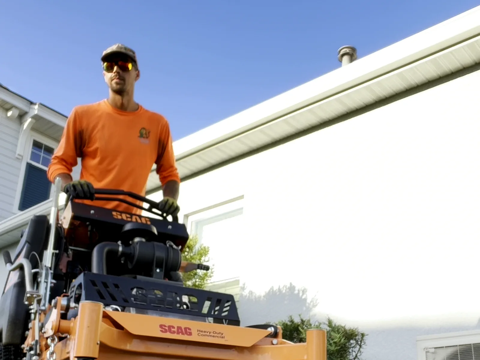 Alex mowing on the Scag stand-on mower in a Squirrel's Friend shirt